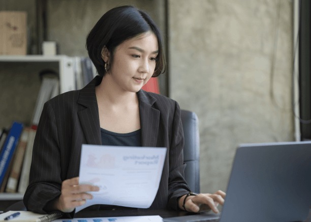 A translator compares French and English university transcripts at a desk, providing French Translation Services in Miami.